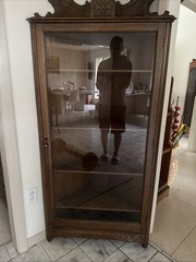 This is a Victorian-style oak curio cabinet carved top and a single glass door